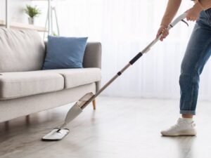a person cleaning the floor with a hard floor spray mop